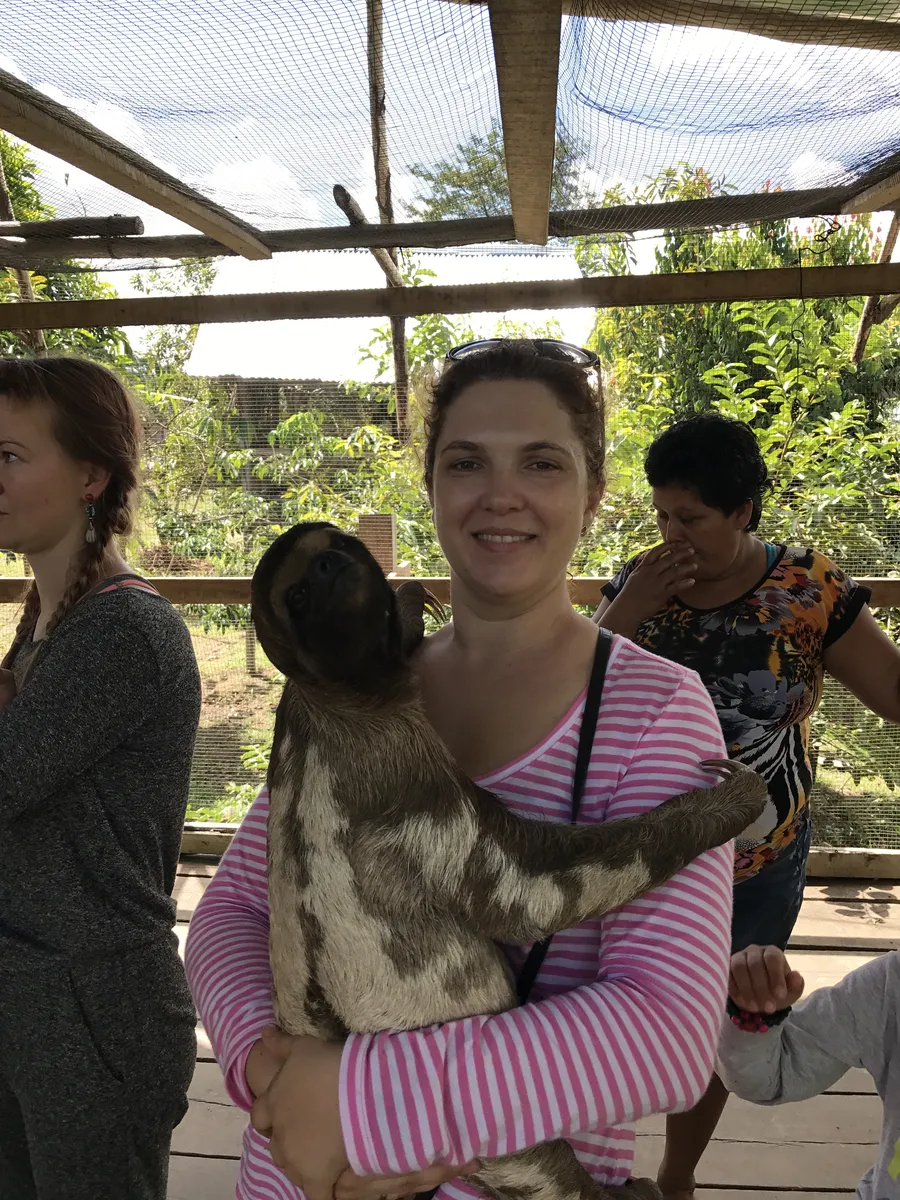 Visitor holding a rescued sloth at an animal rescue center near Iquitos
